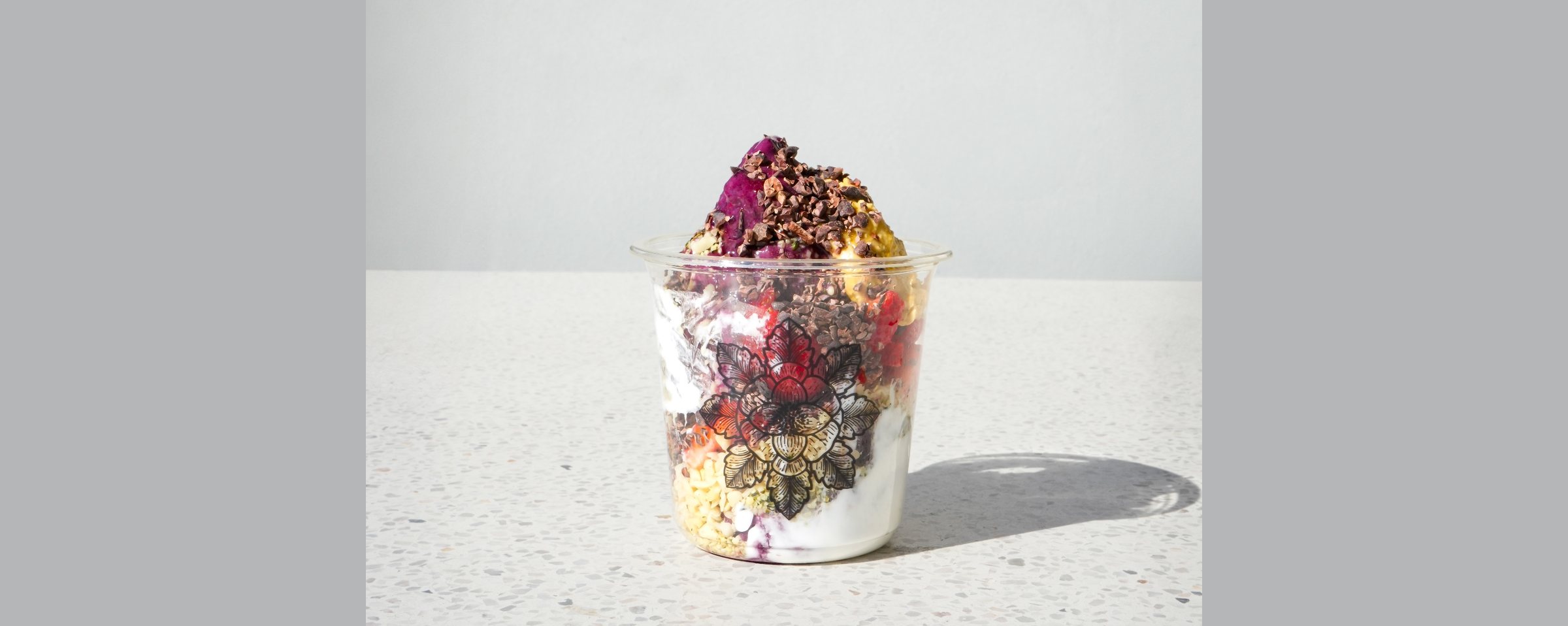 E+ROSE layered smoothie bowl with dragon fruit, berries, granola, and coconut yogurt in a lotus-print cup